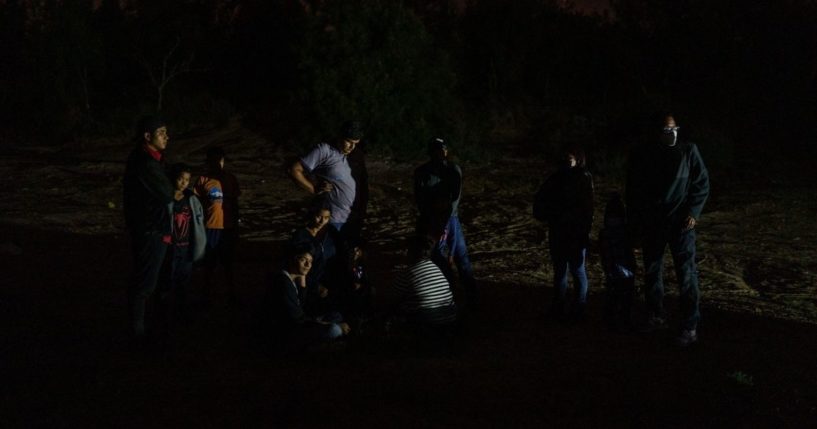 Migrants wait for a National Guard vehicle to pull up on the banks of the Rio Grande after crossing the U.S.-Mexico border on a raft into the United States in Roma, Texas, on July 9, 2021.