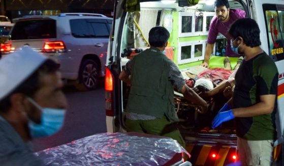 Medical staff bring an injured man to a hospital in an ambulance after two powerful explosions, which killed at least six people, outside the airport in Kabul on Thursday.