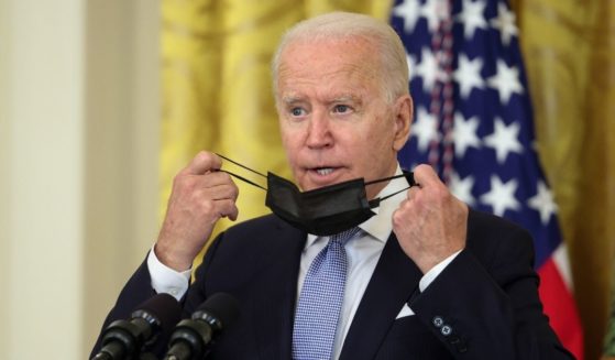 President Joe Biden takes off his face prior to delivering remarks in the East Room of the White House on Thursday.