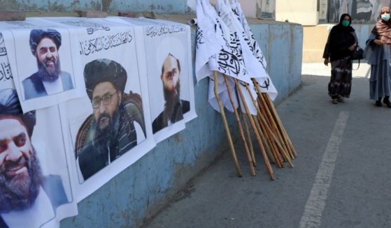 Afghan women walk by posters of Taliban leaders and flags in Kabul, Afghanistan, last week.