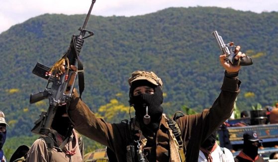 Masked Zapatista Subcommander Marcos smokes a pipe and displays weapons Feb. 24, 2001, in La Realidad, Mexico.