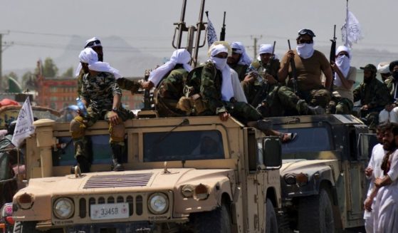 Taliban fighters atop Humvee vehicles parade along a road in Kandahar on Wednesday to celebrate after the U.S. pulled all its troops out of Afghanistan.