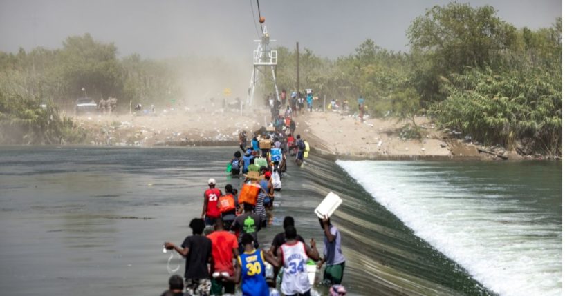 A group of migrants are seen walking toward the international bridge in Del Rio, Texas, on Saturday.