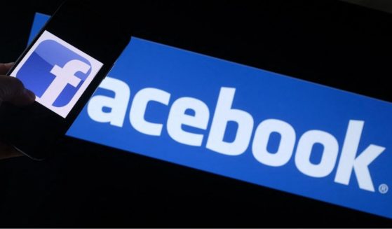 The Facebook logo is seen on a smartphone with a computer screen in the background in Los Angeles on Aug. 12.
