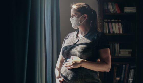 A pregnant woman wearing a mask is seen in this stock image.