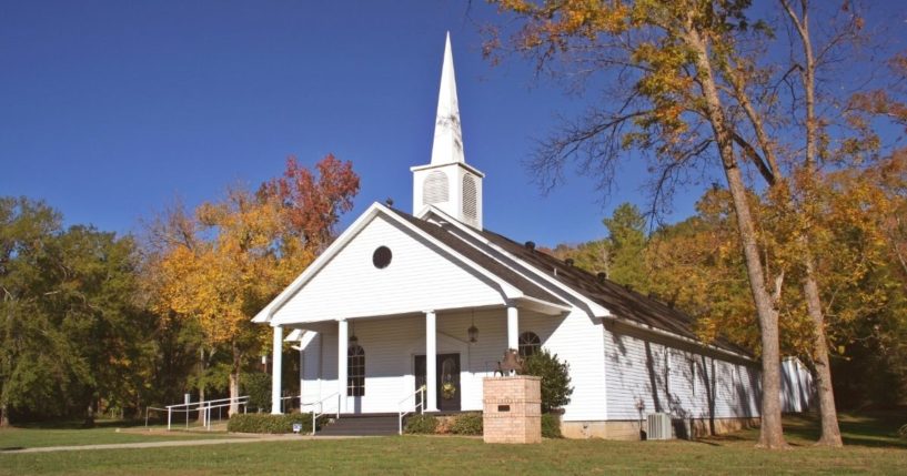 Small church in autumn with fall leaves and blue sky