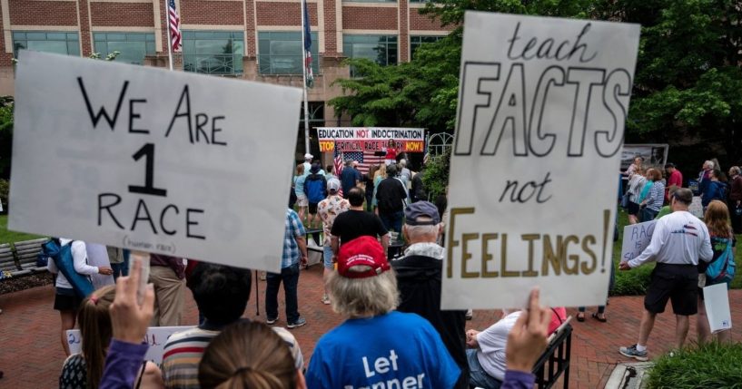 People hold up signs during a rally against critical race theory being taught in schools at the Loudoun County Government Center in Leesburg, Virginia, on June 12.