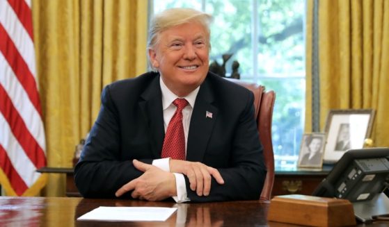 Then-President Donald Trump talks to reporters while hosting workers and members of his Cabinet for a meeting in the Oval Office at the White House on Oct. 17, 2018.