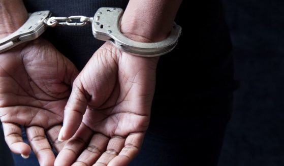 A stock photo shows a woman in handcuffs.