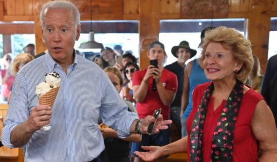 President Joe Biden eats ice cream while standing next to Michigan Sen. Debbie Stabenow at Moomers Homemade Ice Cream in Traverse City, Michigan, on July 3.