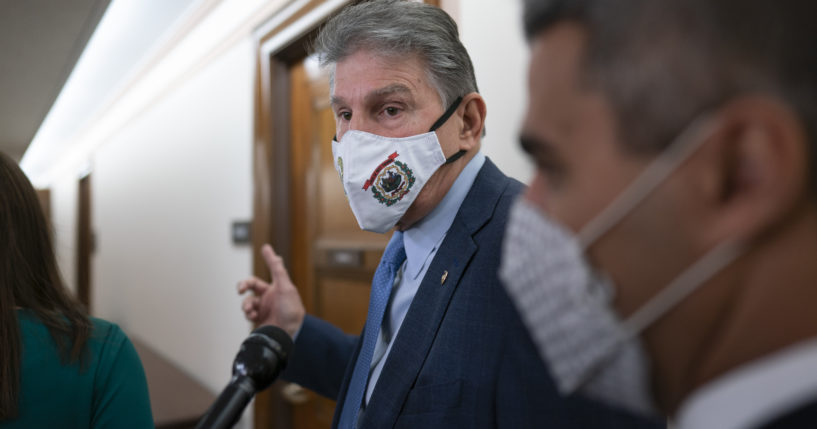 Democratic Sen. Joe Manchin of West Virginia, a key vote on President Joe Biden's domestic spending agenda, tells reporters he's late for a hearing and can't talk at the Capitol on Dec. 2.