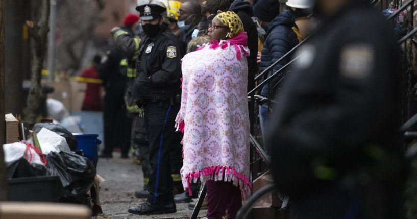 Bystanders watch as the Philadelphia fire department works at the scene of a deadly row house fire in Philadelphia Wednesday.