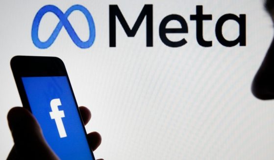 The Facebook logo is displayed on the screen of an iPhone in front of a Meta logo on Oct. 29, 2021, in Paris.