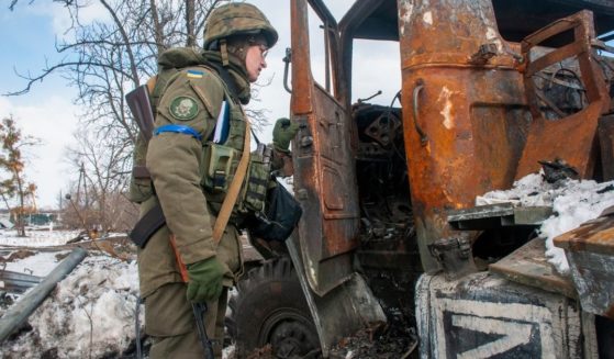 A Ukrainian National guard soldier inspects a Russian damaged military vehicle