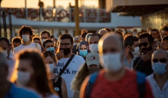 A crowd of people wearing masks is seen in this stock image.
