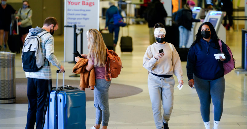 ravelers wearing masks intended to help stop the spread of the coronavirus move about a terminal at the Philadelphia International Airport on April 19, 2022.