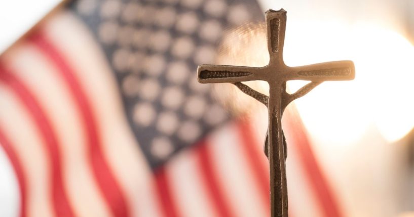 The American flag and a cross are seen in the above stock image.