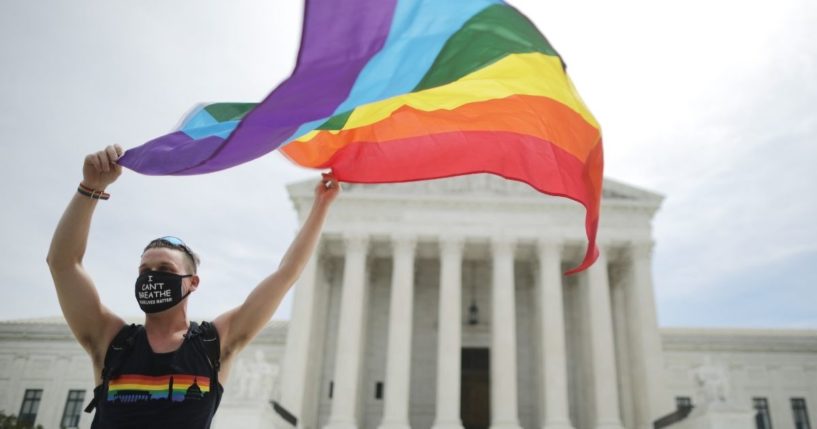 A man holds an LGBT flag in front of the U.S. Supreme Court in Washington, D.C., on June 15, 2020.