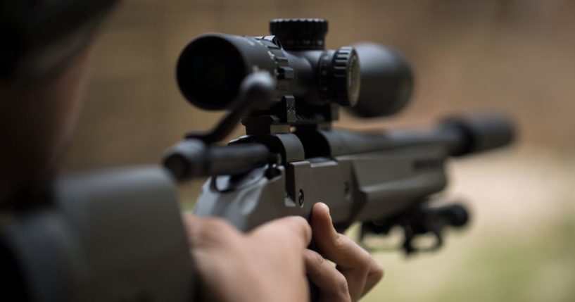 A man shoots a rifle in this stock image.