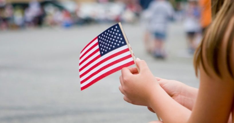 A girl holds an American flag in this stock image.