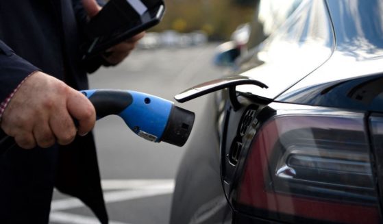 A man charges his Tesla EV after parking at a supermarket in north London on November 18, 2020.