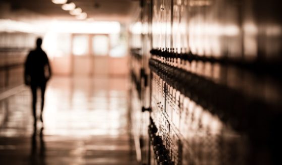 A student walks down a hallway full of lockers in a public high school.