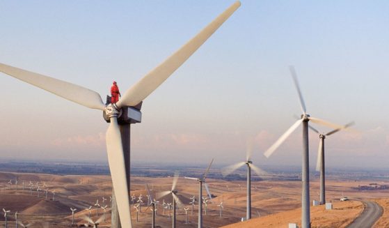 A wind turbine worker is dwarfed by the machinery in this undated file photo taken at Altamont Pass, California.