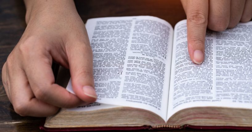 A man reads the Bible in the above stock image.