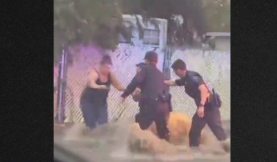 The officers struggled to stay on their feet in the flash flood as they helped a woman and her two children who were swept away by the fast-moving water.