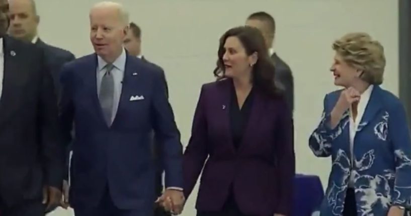 President Joe Biden, left, holds hands with Michigan's Gov. Gretchen Whitmer, right, at the Detroit Auto Show.