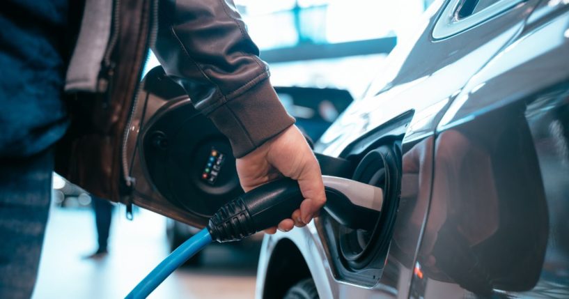 A man charges an electric car in this stock image.