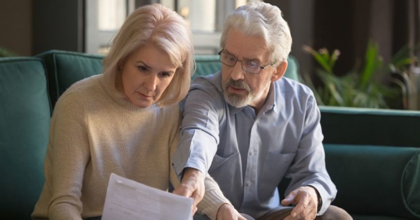 a serious gray-haired mature couple calculating bills