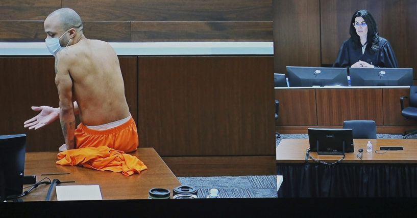 Darrell Brooks sits shirtless in an empty court room after being removed from the first day of his trial for continuously interrupting Waukesha County Circuit Judge Jennifer Dorow, on screen to the right. Brooks is accused of killing six people and injuring dozens more when he allegedly drove his SUV through a Christmas parade in Wisconsin last year.