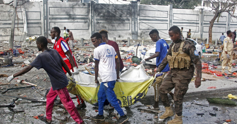 Rescuers remove a body from the scene of two car bomb attacks in Mogadishu, Somalia, Saturday. The bombs exploded Saturday at a busy junction in Somalia's capital near key government offices, leaving "scores of civilian casualties," police told state media.