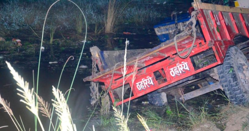 A tractor on the edge of a pond.