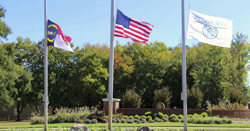 The North Carolina flag, American flag and Hedingham flag all fly at half-staff at the entrance to the Hedingham Golf Club in Raleigh, N.C., on Friday after a shooting in the community left five dead Thursday night, including one off-duty police officer.