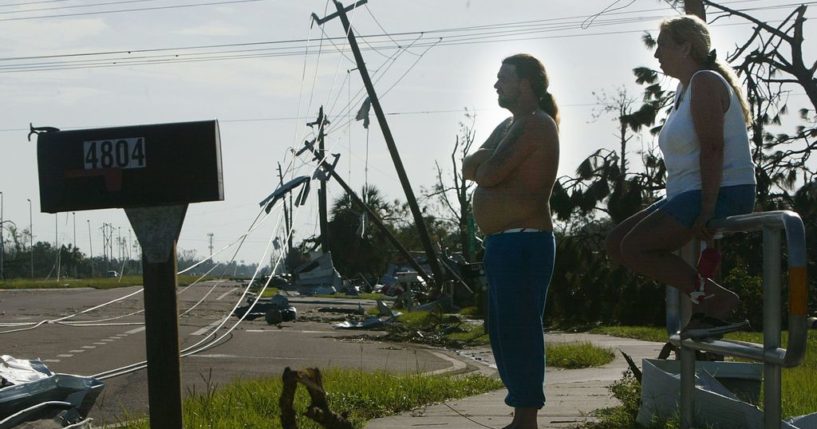 Cindi Norris (R) and Frank Jones survey the scene near their mobile home where they took cover when Hurricane Charley struck in the Pine Acres mobile home community August 15, 2004 in Punta Gorda, Florida. Hurricane Charley destroyed most of the mobile homes in the area but left theirs largely intact. (Photo by Mario Tama/Getty Images)