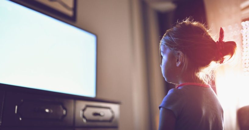 A girl watches TV in the above stock image.