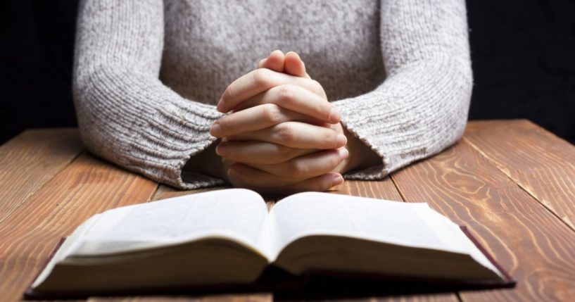 A woman prays in the above stock image.