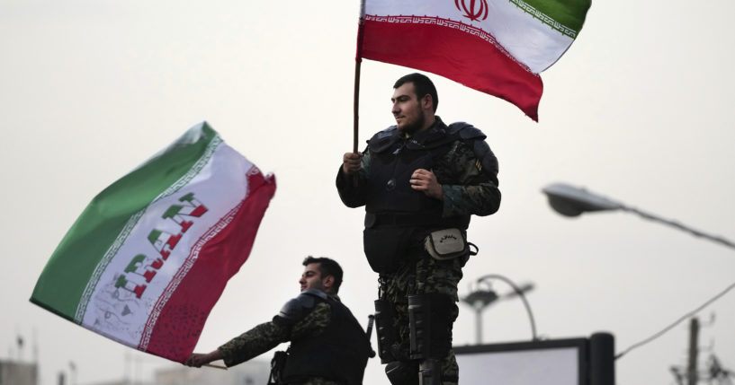 Two anti-riot police officers wave Iranian flags during a street celebration after Iran defeated Wales in the World Cup on Friday.