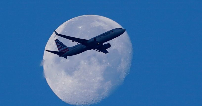 An American Airline Boeing 737 flies past the moon as it heads to Orlando, Florida, from Miami International Airport in Miami on April 19.