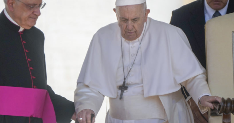 Pope Francis is helped by his aide Monsignor Leonardo Sapienza, left, as he walks with a cane to his weekly general audience in St. Peter's Square at The Vatican, on June 1.