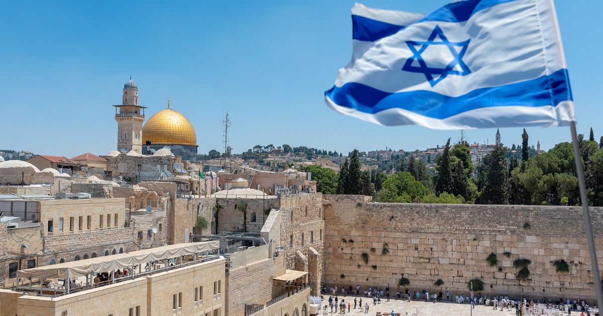 An Israeli flag blows in the wind from an elevated view of the Western Wall.
