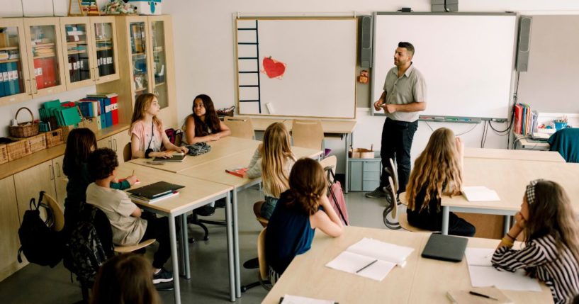 A stock photo shows a male instructor teaching middle school students.