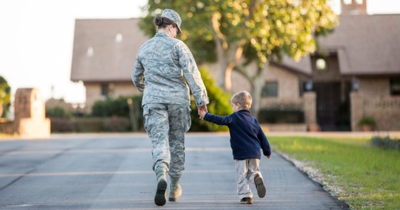 A service member walks alongside her child.