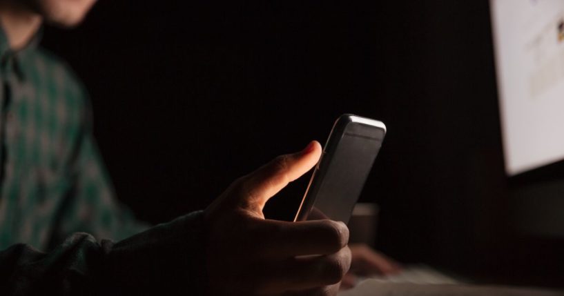 A man looks at a cellphone in the above stock image.