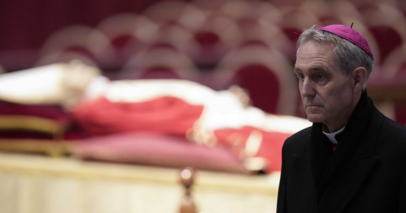 The body of Pope Emeritus Benedict XVI lies in state as father Georg Gaenswein stands on the right inside St. Peter's Basilica at the Vatican on Monday.