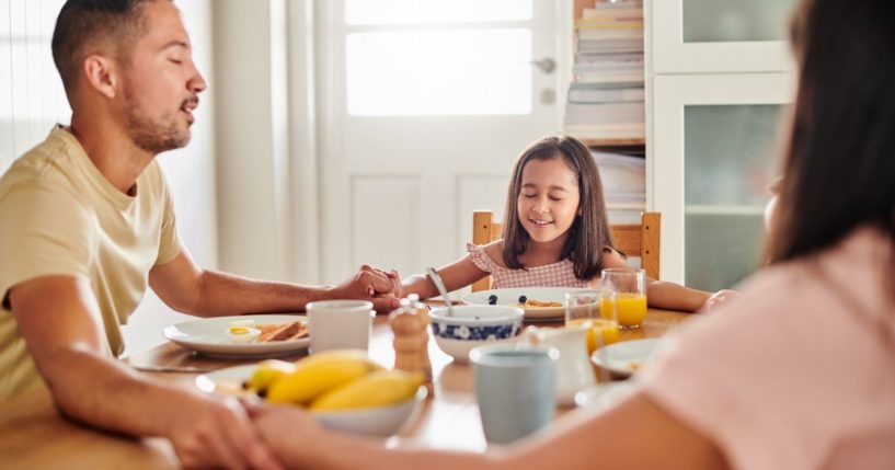 A family prays together in the above stock image.