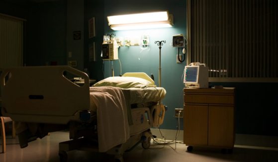 This stock photo depicts an empty hospital bed in a darkened room.