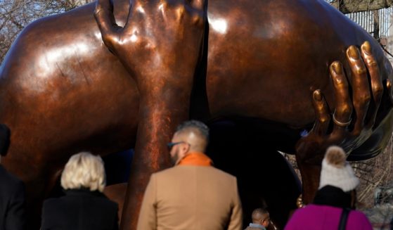 Viewers stand near the 20-foot-high bronze sculpture "The Embrace," a memorial to Dr. Martin Luther King Jr. and Coretta Scott King, in the Boston Common on Tuesday in Boston.